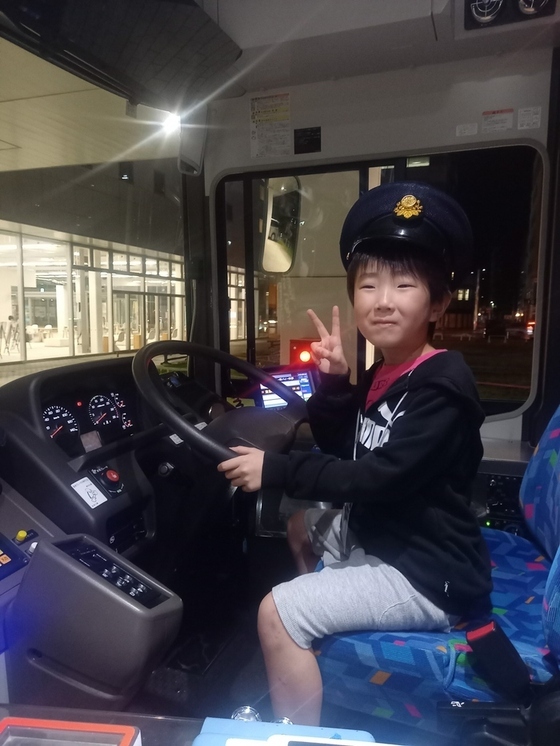 バスの運転席に座る男の子の写真